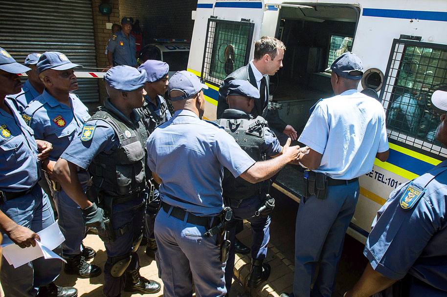Un gruppo di poliziotti fa scudo per permettere a Pistorius di salire sul furgone diretto al carcere (Olycom)